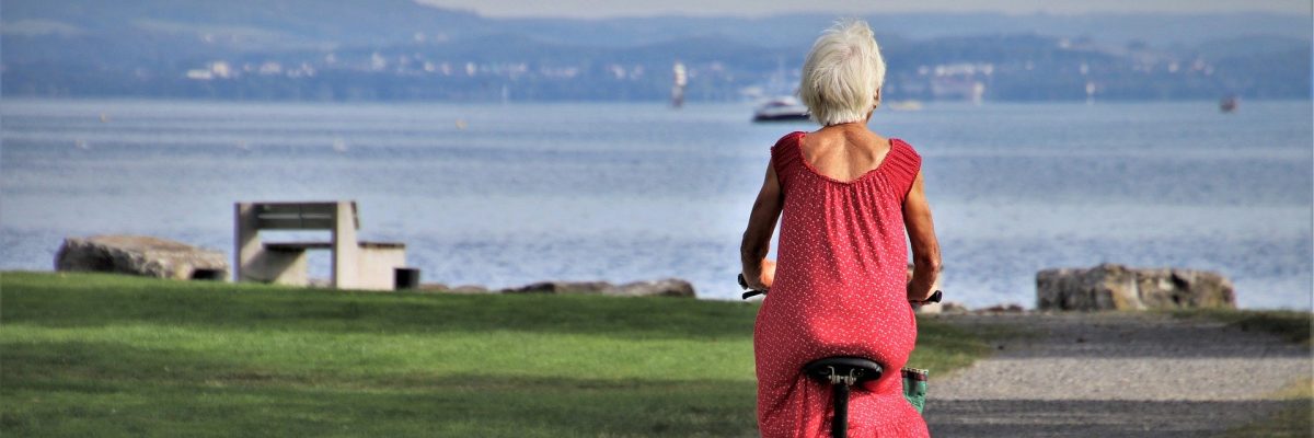 ältere Frau fährt mit Rad zum Strand