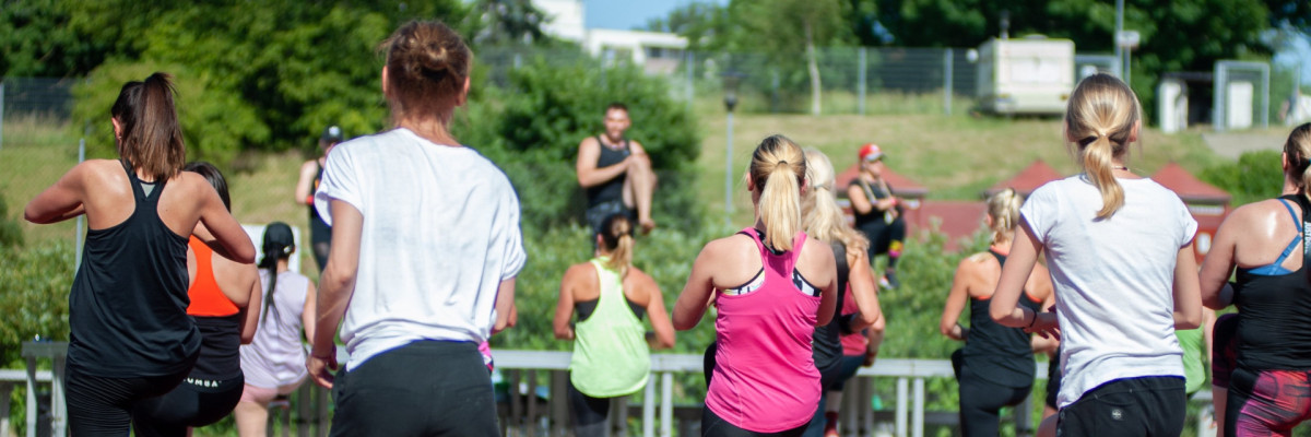 Menschen die im Freien Gymnastikübungen absolvieren.