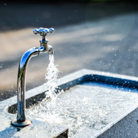 Wasserhahn mit sprudelndem Wasser in einem öffentlichen Brunnen in Wien
