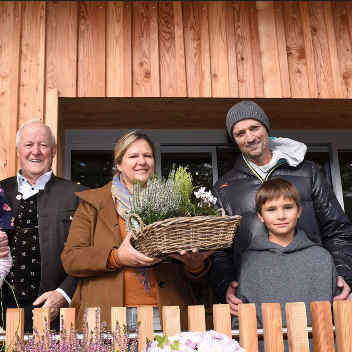 Familie vor Holzhaus mit Blumenkorb in Österreich
